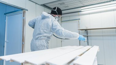 Marangoz boya odasında daha sonra atölyesinde kullanmak üzere bir tahta parçası püskürtüyor. Yüksek kalite fotoğraf