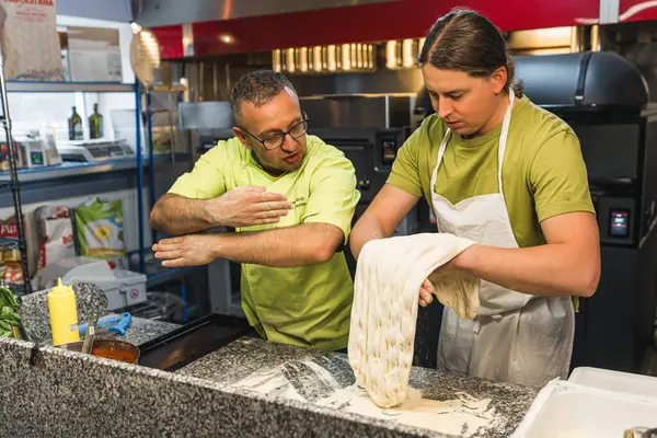 Baş aşçı öğrencisine pizza için nasıl mükemmel hamur yapılacağını anlatıyor. Yüksek kalite fotoğraf