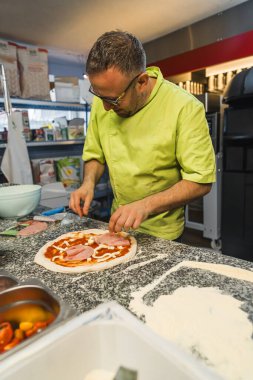 Pizza hazırlamak için et ve baharat ekleyen bir adamın dikey çekimi. Yüksek kalite fotoğraf