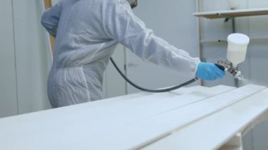 Fabrikada usta bir ressam. Endüstriyel boyada sprey silahla odun boyuyor. Yüksek kalite 4k görüntü