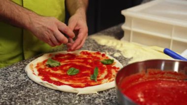 Aşçı fırında margarita pizza yapmak için pizzaya ıspanak ekliyor. Yüksek kalite 4k görüntü