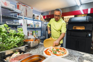 Aşçı, pizzayı kabuğuyla alıp restoran mutfağındaki elektrikli fırına koyar. Yüksek kalite fotoğraf