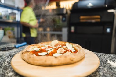 Tahtada salatalık ve domatesli pizza, arkada da aşçı. Yüksek kalite fotoğraf