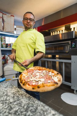 Mutfakta elinde mantarlı pizza tutan bir adam, dikey çekim. Yüksek kalite fotoğraf