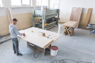 Genç erkek marangoz ya da işveren atölyede elektrikli zımpara makinesi kullanıyor. Yüksek kalite fotoğraf