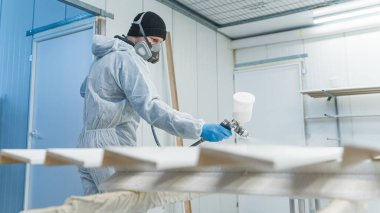 Marangoz boya odasında daha sonra atölyesinde kullanmak üzere bir tahta parçası püskürtüyor. Yüksek kalite fotoğraf