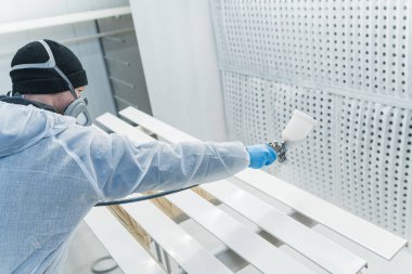 Solunum maskeli bir adam atölyedeki tahtaları boyuyor. Modern mobilya fabrikası boyası ustası. Yüksek kalite fotoğraf