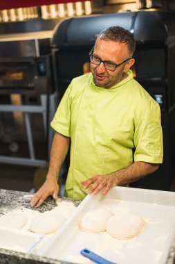 Şef fırında pizza yapmak için hamur hazırlamaya hazır, dikey çekim. Yüksek kalite fotoğraf