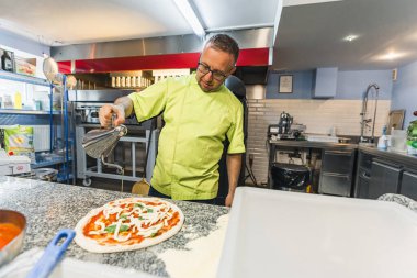 Şef pizzaya zeytinyağı ekliyor ve pişirmeye hazırlanıyor, pizzacı. Yüksek kalite fotoğraf