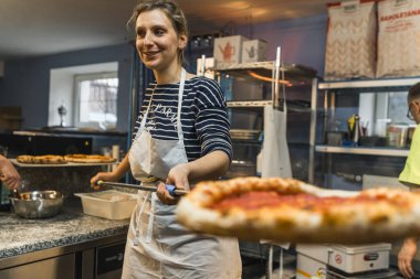 Genç bayan aşçı fırında çalışıyor ve pizza hazırlıyor. Yüksek kalite fotoğraf