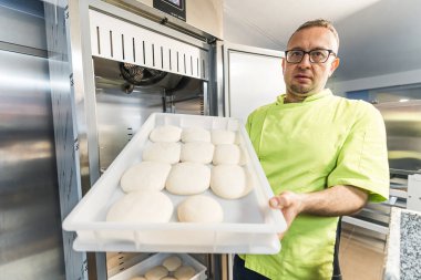 Şef pizzacıda pizza hamuru toplarını kameraya doğru tutuyor. Yüksek kalite fotoğraf