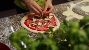 Restoranın mutfağında pizzaya mantar ekleyen bir şefin yakın plan fotoğrafı. Yüksek kalite 4k görüntü