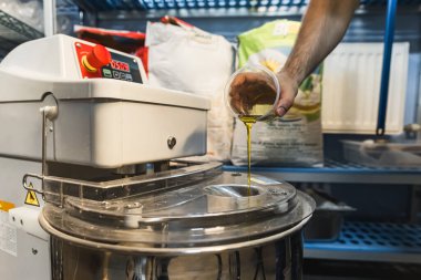 Otomatik endüstriyel karıştırıcıya zeytinyağı eklemek hamuru yoğurmak, mutfak konsepti. Yüksek kalite fotoğraf