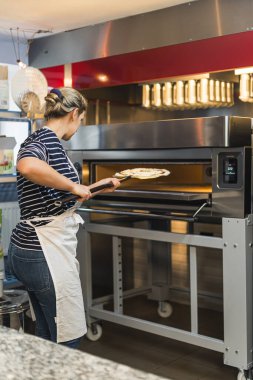 Bir kadının pizza pişirip fırına koyduğu dikey pozlar, mutfak. Yüksek kalite fotoğraf