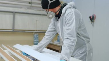 Fabrikada üniforması olan genç bir adam ahşap bir parçaya sprey sıkar. Yüksek kalite 4k görüntü