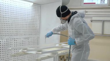 Solunum maskeli bir adam atölyedeki tahtaları boyuyor. Modern mobilya fabrikası boyası ustası. Yüksek kalite 4k görüntü