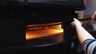 04.04.2024. Varşova, Polonya. Pizzayı kabuklu elektrikli fırına koymak, restoran mutfağında çalışmak. Yüksek kalite 4k görüntü