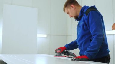Erkek marangoz, atölyesindeki bir odun parçası üzerinde zımpara kullanıyor ve işine odaklanıyor. Yüksek kalite 4k görüntü