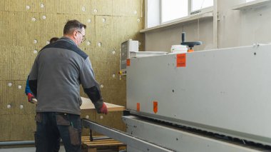 Modern bilgisayar makinesinde çalışan ve fabrikada ahşap kalaslarla çalışan işçiler. Yüksek kalite fotoğraf