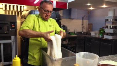 Pizza hamuru üzerinde çalışan orta yaşlı bir aşçı. Yüksek kalite 4k görüntü
