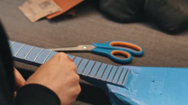 Adam atölyede modern elektro gitarın ayrıntıları üzerinde çalışıyor. Yüksek kalite 4k görüntü