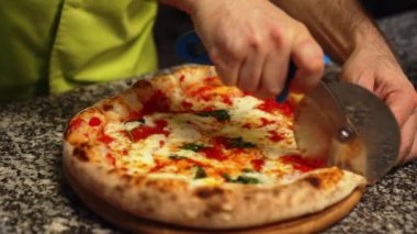 Aşçı pizza margherita 'yı pizza bıçağıyla kesiyor. Mutfaktaki tahta tahtada. Yüksek kalite 4k görüntü