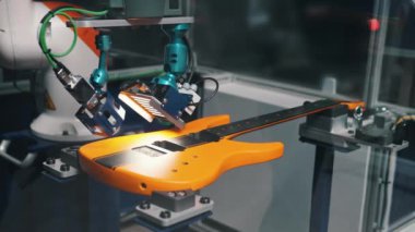 Fabrikadaki modern gitarın kalitesini kontrol ediyorum, robot kolu. Yüksek kalite 4k görüntü