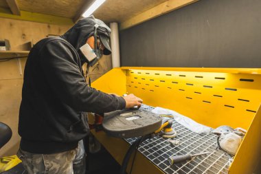 Gitarı cilalayan maskeli bir adam, yeni bir gitar yapıyor. Yüksek kalite fotoğraf