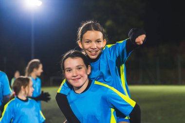 Futbol oyuncusu küçük kızlar akşam antrenmanında kameraya poz veriyorlar, orta ölçekli. Yüksek kalite fotoğraf