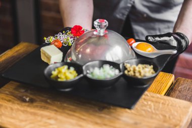 Gurme tartar ve aksesuarların canlı bir düzenini deneyimleyin, sanatsal olarak karanlık bir tabakta sunuluyor, aşçılık sanatını sergiliyor ve yemek meraklıları için mükemmel lezzetler sunuyor..