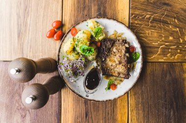 Izgara et, canlı sebzeler ve baharatlı haşlanmış patateslerden oluşan lezzetli bir ev yapımı yemeğin yakın çekimi, güzel bir ahşap masa üzerinde konforlu ve davetkar bir ortam..