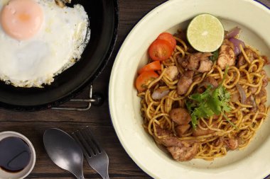 Kızarmış sarı şehriye geleneksel mee gorng domates maydanozlu limon mineli metal tabak üzerinde güneşli tarafı tava çatalı kaşığı koyu soya soslu yumurta. 