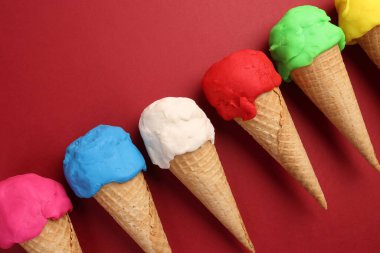 Sahte modelleme kil çok renkli dondurma waffle bisküvi koni düz kırmızı zemin üzerinde yatıyordu 