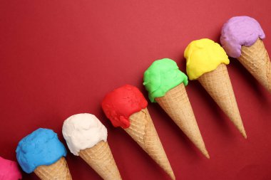 Sahte modelleme kil çok renkli dondurma waffle bisküvi koni düz kırmızı zemin üzerinde yatıyordu 