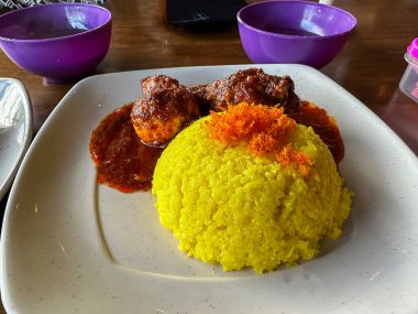 Traditional Sabah food nasi kuning yellow sticky rice served with chicken cooked rendang style and red curry masak merah