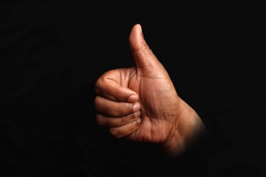 Asian dark skin top view hand fist thumps up  sign on black background 