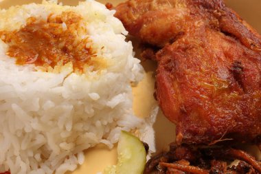 Bol yağda kızartılmış baharatlı tavuk, salatalık salatası, ançüez fıstık sosu, Nasi kukus ayam ayam goreng berempah ile servis edilmiş. 