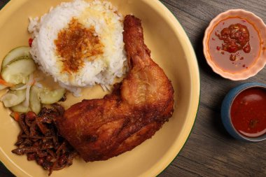 Bol yağda kızartılmış baharatlı tavuk, salatalık salatası, ançüez fıstık sosu, Nasi kukus ayam ayam goreng berempah ile servis edilmiş. 