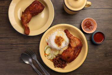 Bol yağda kızartılmış baharatlı tavuk, salatalık salatası, ançüez fıstık sosu, Nasi kukus ayam ayam goreng berempah ile servis edilmiş. 