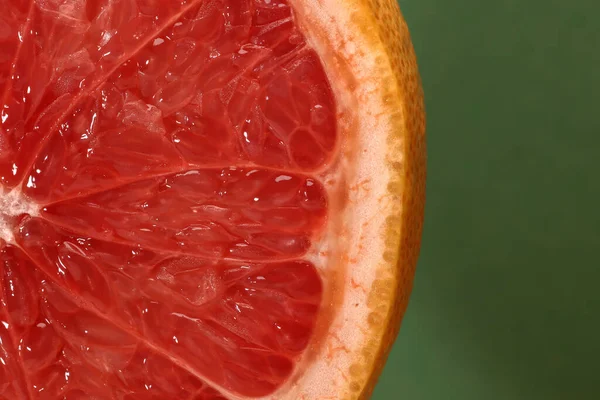 stock image Half cut sliced ruby red grapefruit pulp macro closeup green background 