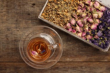 Kuru çiçek çayı kelebek bezelye çiçeği şeffaf cam çay fincanı kırsal ahşap masa arka planında 