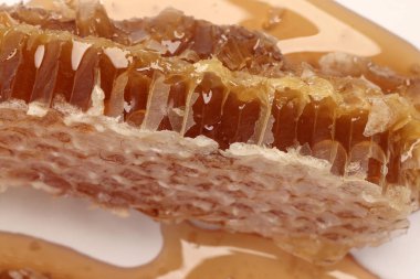 Yapışkan sıvı bal doğal jeomatik altıgen bal peteği makrosu beyaz arkaplanda yakın plan 