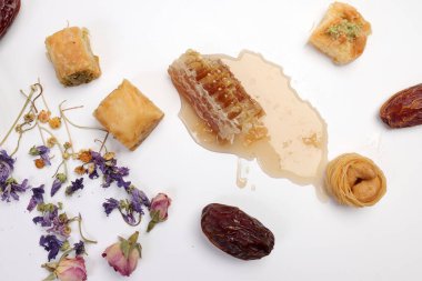 Doldurulmuş hamur işi Baklava tatlı tatlı tatlı meyve suyu bal doğal jeomatik balmumu bal peteği çiçekli gül goncası kelebek papatya çiçeği çiçeği çayı şeffaf cam bardak fincanda beyaz zemin üzerinde çay 