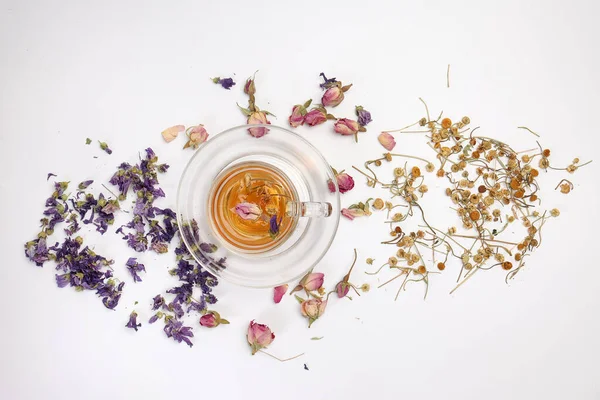 stock image Dry flower tea rose bud butterfly pea chamomile flower transparent ceramic glass tea cup on white background 