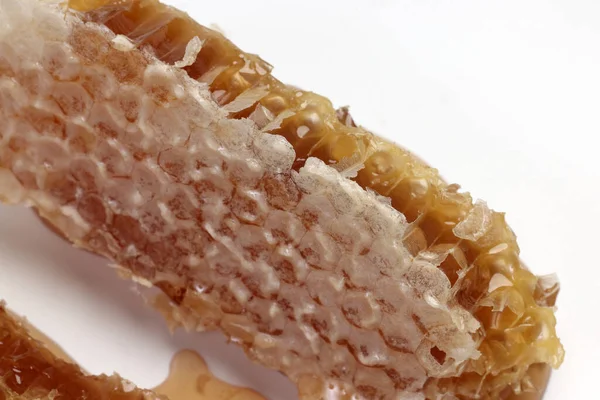 粘りのある液体蜂蜜自然地理的六角形ハニカムマクロ白い背景にクローズアップ — ストック写真