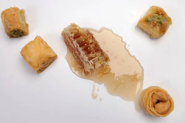 stock image Layered stuffed pastry Baklava sweet dessert  date fruit liquid honey natural geomatic hexagon bee wax honeycomb  flower tea rose bud butterfly pea chamomile flower tea in transparent glass cup saucer on white background 