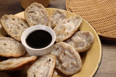 Kabarık pirinç tozu krepi Bengali chitoi Dhaka Chikui Sora pitha kırsal ahşap masa zemininde sıvı pekmez ile servis edilir. 