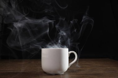 Siyah arka planda beyaz seramik kahve fincanından çıkan duman bulutu. 