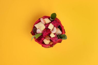 Güzel Mangosteen mango ejderhası küp meyve salatası içinde ejderha meyve kabı sarı arka planda yeşil muz yaprağı 