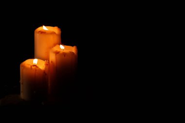 Siyah arka planda dans eden üç mum yanıyor. 